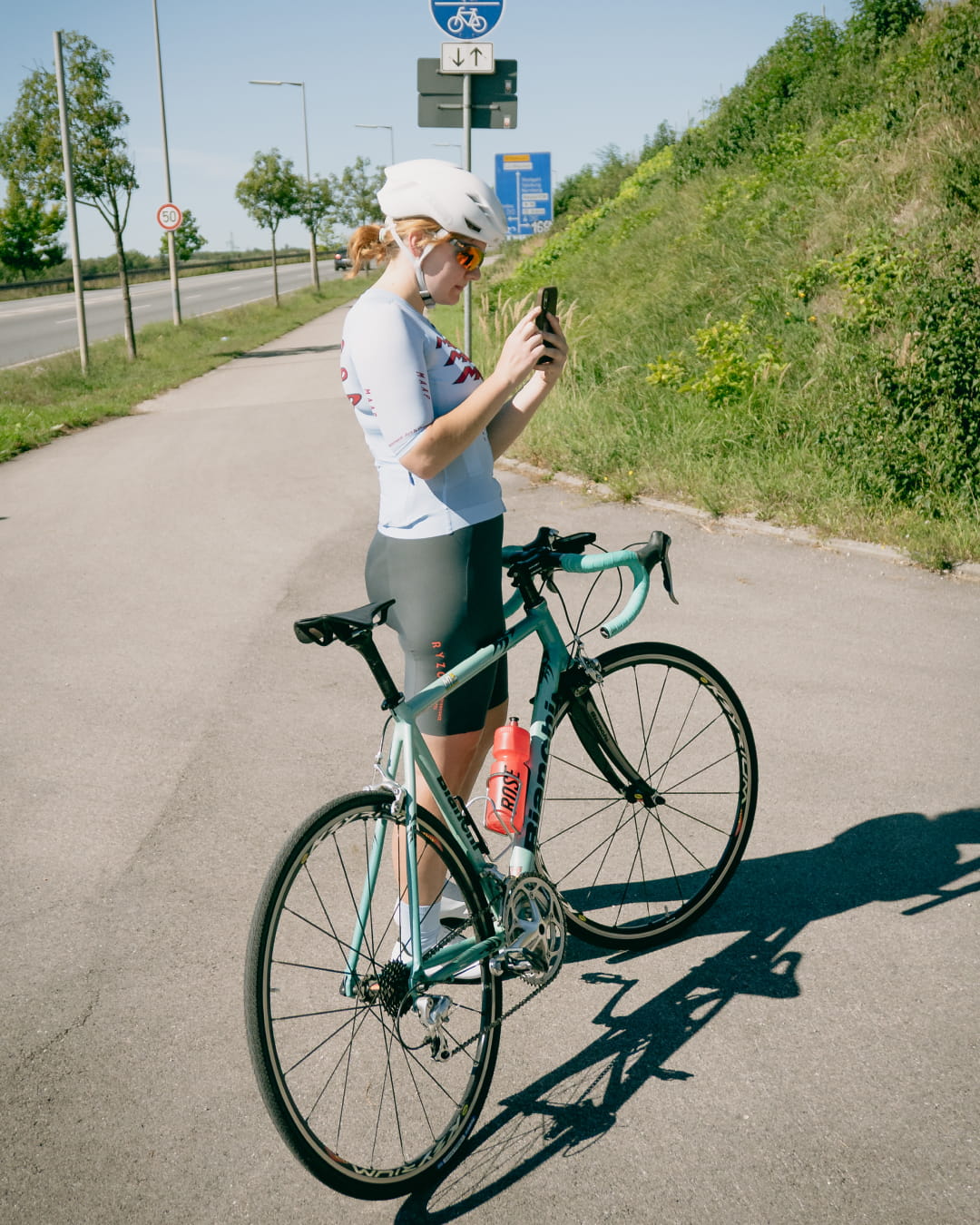 Fahrerin mit Bianchi-Rennrad schaut aufs Handy
